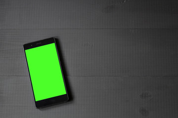 smartphone with green screen on wooden table