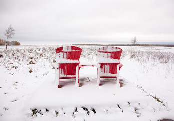 two red Adirondack chairs on snowy field