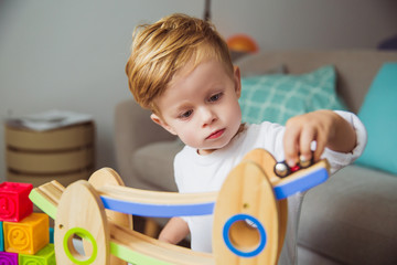 Portrait of little serious boy who playing with toys in the room