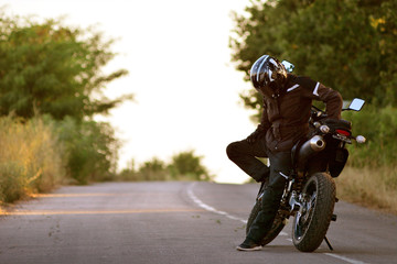 Lonely motorcyclist in helmet looking at the ground. Lyrical statement with a thoughtful motorcyclist. 