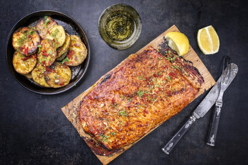 Barbecue salmon fillet marinated on cedar plank wood with fries as overhead view