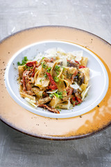 Traditional Italian pappardelle di pomodoro with mushrooms and parmesan as close-up on a plate