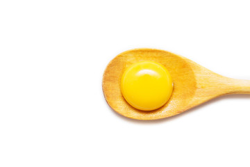 Raw Egg yolk in a wooden spoon on a bright white background