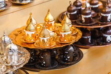Fototapeta na wymiar Tea and coffee set with traditional golden cups on the oriental market bazaar.