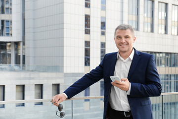 Elegant businessman using mobile phone outdoors