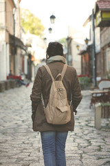 Woman with rucksack is walking in an old city; people and tourism concept.