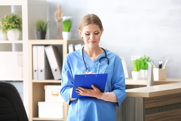 Young female receptionist holding folder with documents in hospital