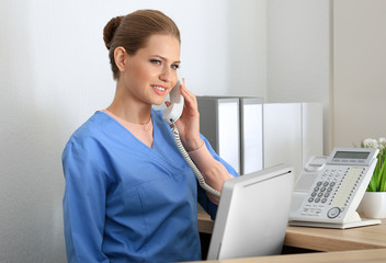 Young female receptionist talking on the phone in hospital