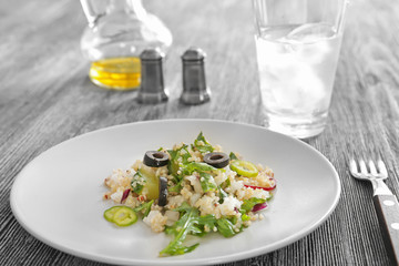 Plate with quinoa salad on wooden table