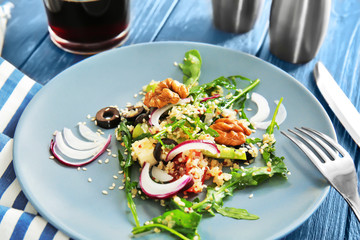 Plate with quinoa salad on wooden table, closeup