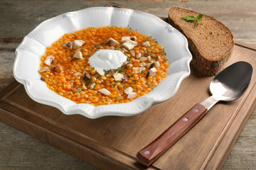 Plate with tasty lentil soup on wooden board
