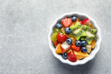 Bowl with yummy fruits salad on grunge table