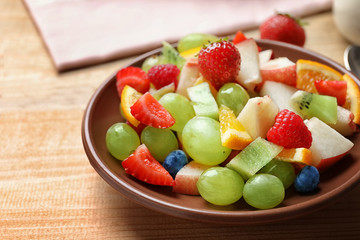 Plate with yummy fruit salad on wooden table
