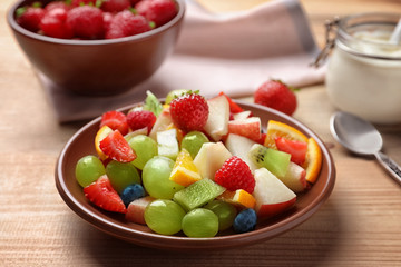 Plate with yummy fruit salad on wooden table