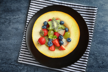 Half of melon with yummy fruit salad on grunge table