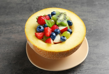 Half of melon with yummy fruit salad on grunge table
