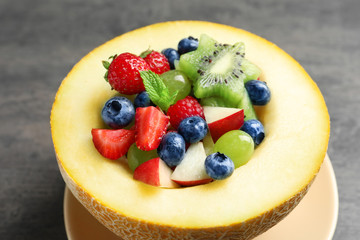 Half of melon with yummy fruit salad on grunge table