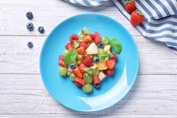 Plate with fruit salad on wooden table