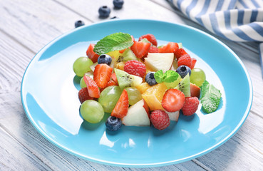 Plate with fruit salad on wooden table