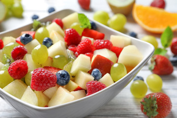 Bowl with yummy fruit salad on wooden table