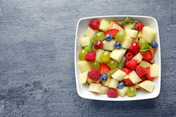 Bowl with yummy fruit salad on grunge table