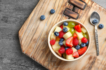 Naklejka na ściany i meble Bowl with yummy fruit salad on wooden board