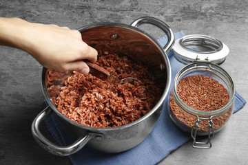 Woman mixing cooked rice with spoon in saucepan