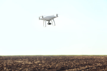 Modern quadcopter flying over field