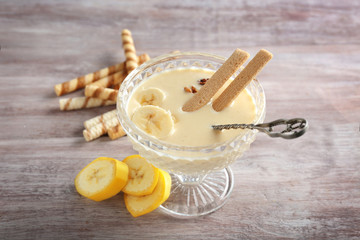 Dessert bowl with tasty banana smoothie on wooden background