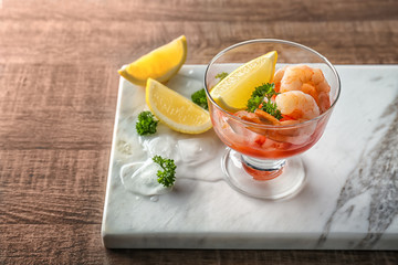 Bowl with shrimp cocktail, lemon and parsley on table