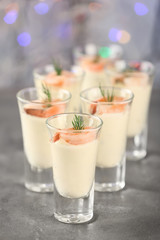 Glasses of white sauce and shrimps on table against sparkly background, closeup