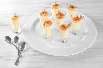 Plate with glasses of white sauce and shrimps on table