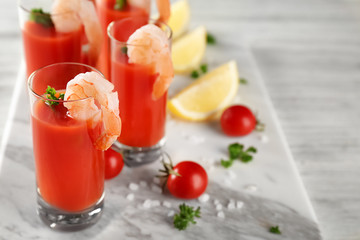 Board with glasses of tomato sauce and shrimps on table, closeup