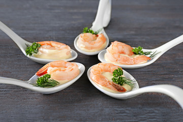 Spoons of white sauce and shrimps on table, closeup