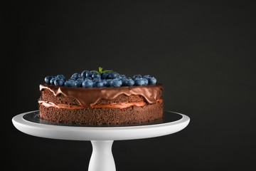 Stand with chocolate cake on black background