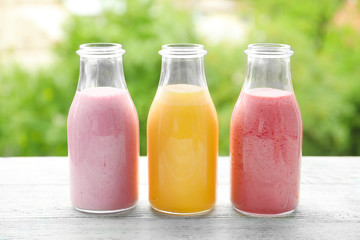 Glass bottles with different protein shakes on blurred background