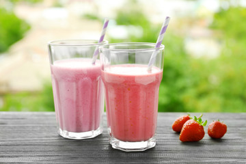 Glasses with different protein shakes on blurred background