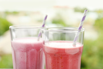 Glasses with different protein shakes on blurred background