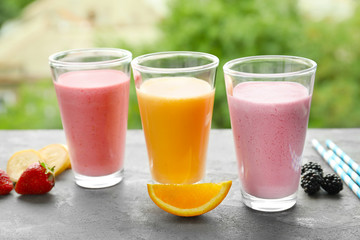 Glasses with different protein shakes on blurred background