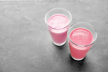Glasses with different protein shakes on grey background