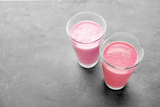 Glasses with different protein shakes on grey background