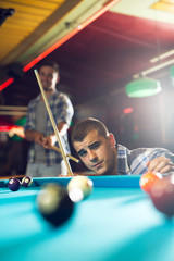 Young handsome man playing pool