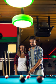 Couple dating and playing billiard in a pool hall