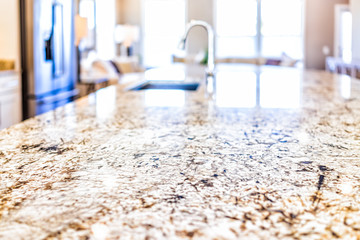 New modern faucet and kitchen room sink closeup with island and granite countertops in model house,...