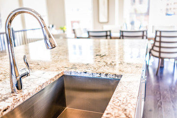 New modern faucet and kitchen room sink closeup with island and granite countertops in model house, home, apartment - obrazy, fototapety, plakaty