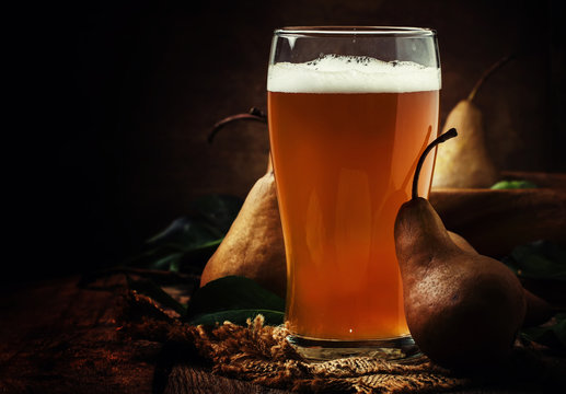 Pear cider in a large beer glass, vintage wooden background, selective focus