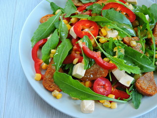 Useful salad with arugula on a plate. Beautiful and tasty fitness salad. Top view.
