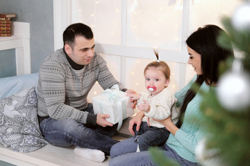 Family mom, dad and daughter at home on the background of Christmas decoration and gifts