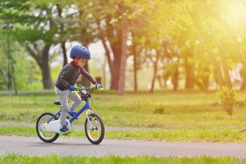 Happy kid boy of 5 years having fun in spring park with a bicycle on beautiful fall day. Active child wearing bike helmet