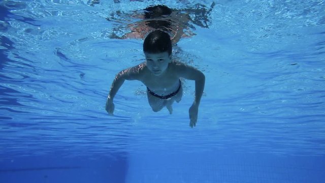 Boy dive in swimming pool underwater slow motion